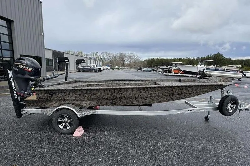 The Image of 2026 Xpress X18DB boat on trailer in parking lot, overcast sky. - 1