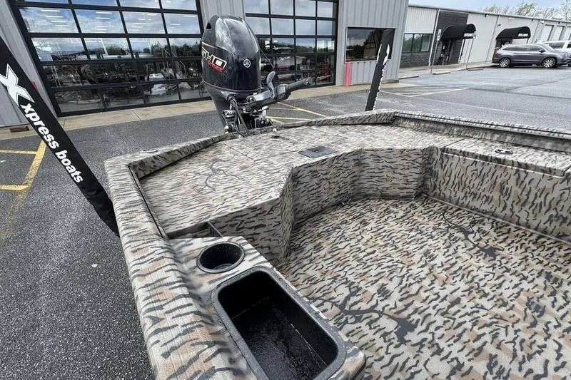 Slide: The Image of 2026 Xpress X18DB boat with camouflage interior and outboard motor in parking lot. - 14