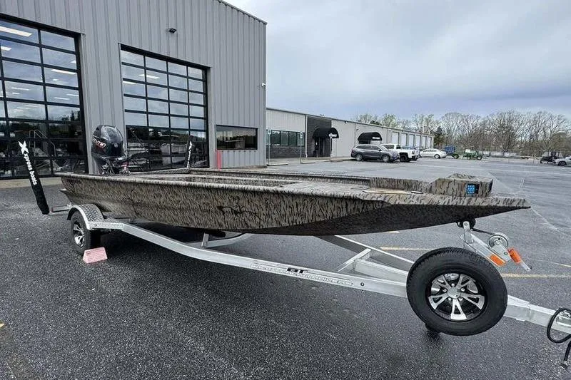 Slide: The Image of 2026 Xpress X18DB boat on trailer in parking lot, near industrial building. - 6
