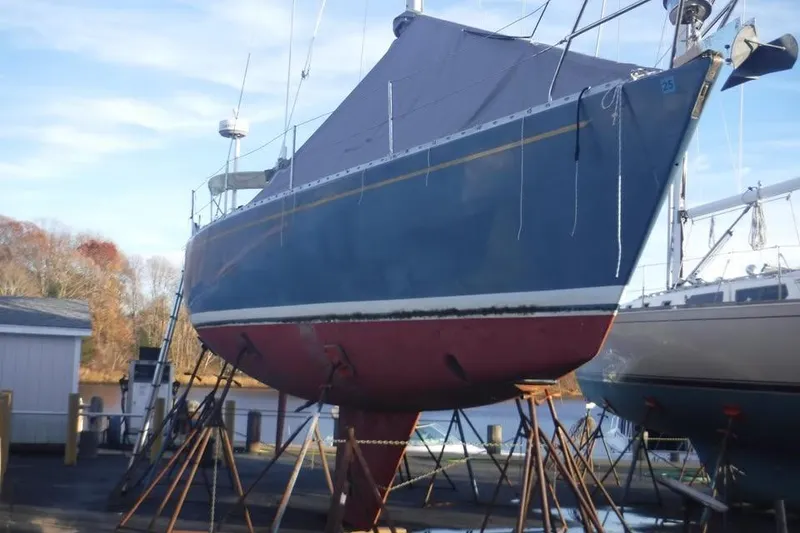 The Image of 1986 Fast Masthead Sloop with Bowthruster on stands, blue hull, red bottom, outdoor setting. - 1