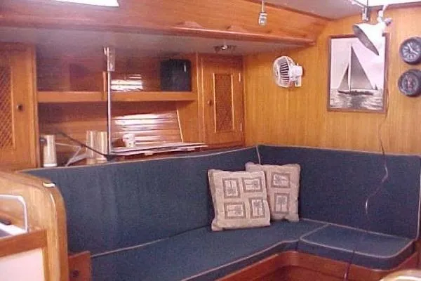 Slide: The Image of Cozy interior of 1986 Fast Masthead Sloop with blue seating and wooden cabinetry. - 18