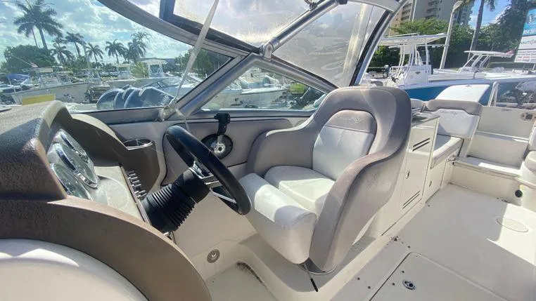 Slide: The Image of 2011 Sea Ray 300 Sundeck interior with steering wheel and seating, docked under sunny skies. - 16
