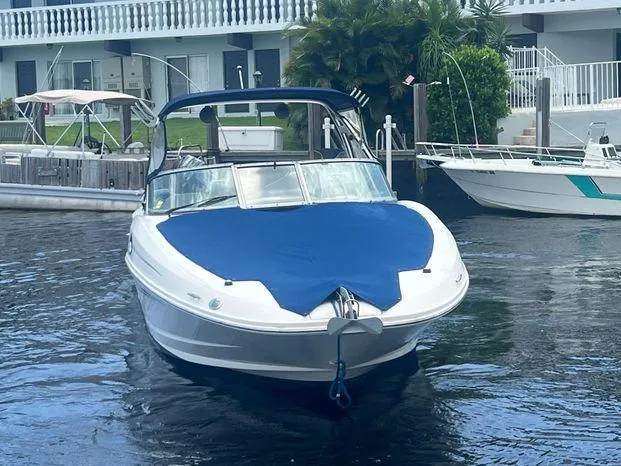 Slide: The Image of 2011 Sea Ray 300 Sundeck boat with blue cover docked in a marina. - 2