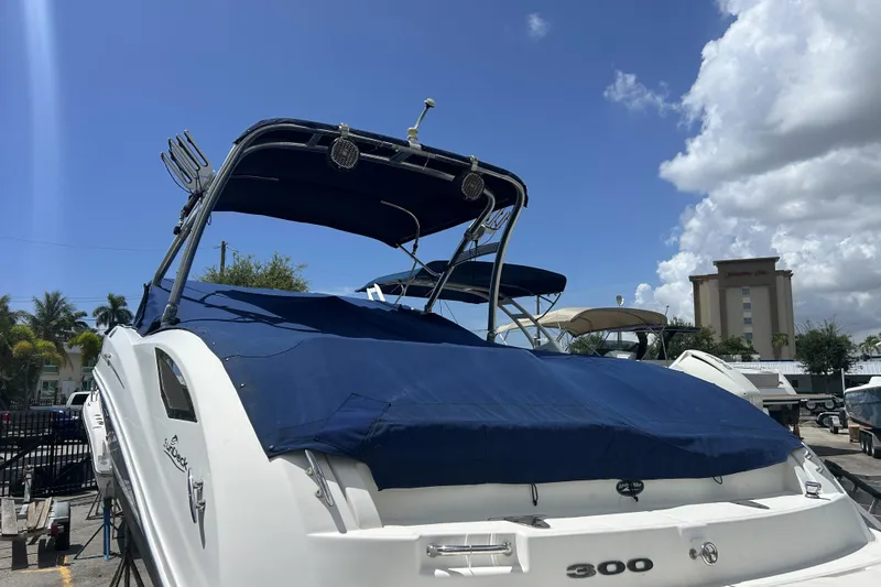 Slide: The Image of 2011 Sea Ray 300 Sundeck boat with blue cover, docked under a clear sky. - 27