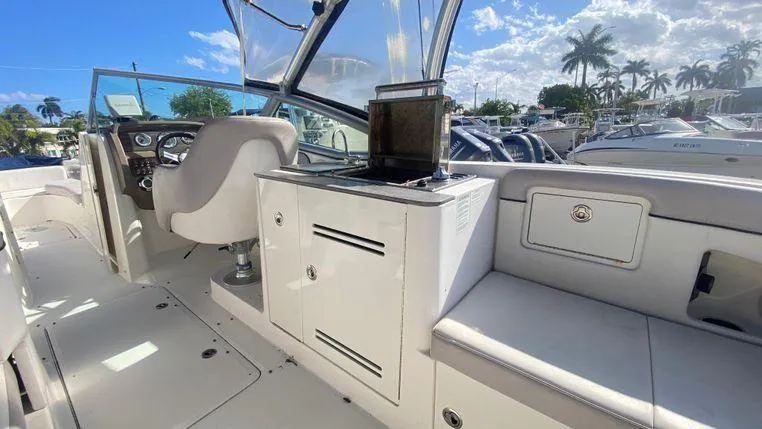 Slide: The Image of 2011 Sea Ray 300 Sundeck interior with helm, seating, and storage under sunny skies. - 5