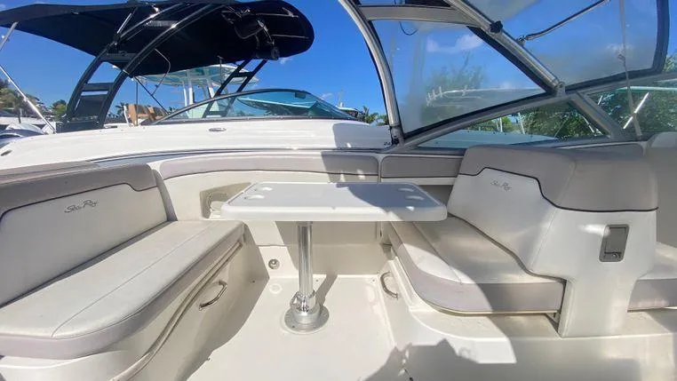 Slide: The Image of 2011 Sea Ray 300 Sundeck interior with seating and table, under clear blue sky. - 6