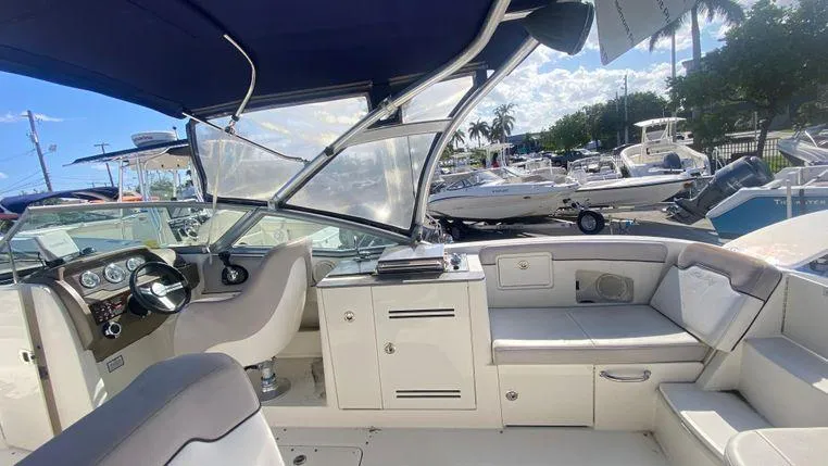 Slide: The Image of 2011 Sea Ray 300 Sundeck interior with helm, seating, and storage, docked under blue sky. - 7