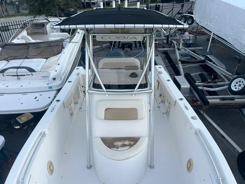 Slide: The Image of 2009 Cobia 216 Center Console boat with T-top, docked alongside other vessels. - 12