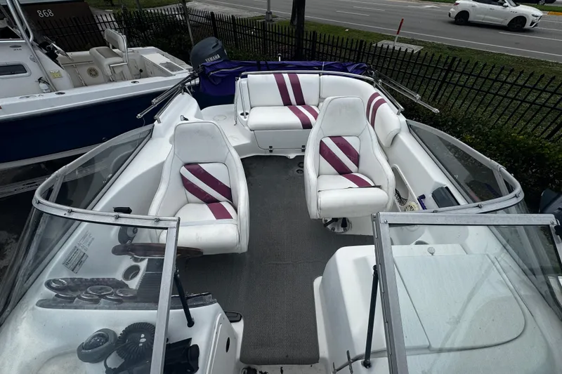 Slide: The Image of 2008 Splendor 240 Sunstar boat with white and purple seating, docked near a road. - 8