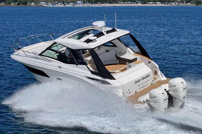 Slide: The Image of 2021 Sea Ray Sundancer 320 Outboard cruising on open water, showcasing sleek design and powerful engines. - 11