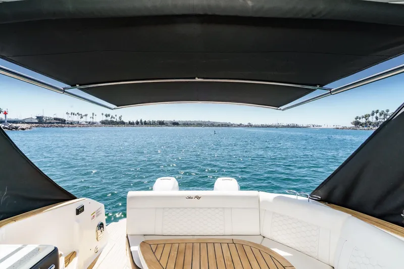 Slide: The Image of 2021 Sea Ray Sundancer 320 Outboard with canopy, overlooking serene ocean view. - 27