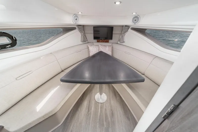 Slide: The Image of Interior of 2021 Sea Ray Sundancer 320 Outboard, featuring a sleek dining area with a triangular table. - 47