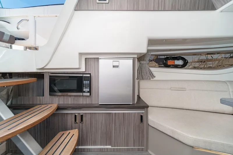 Slide: The Image of 2021 Sea Ray Sundancer 320 Outboard interior with kitchenette, microwave, and seating area. - 49