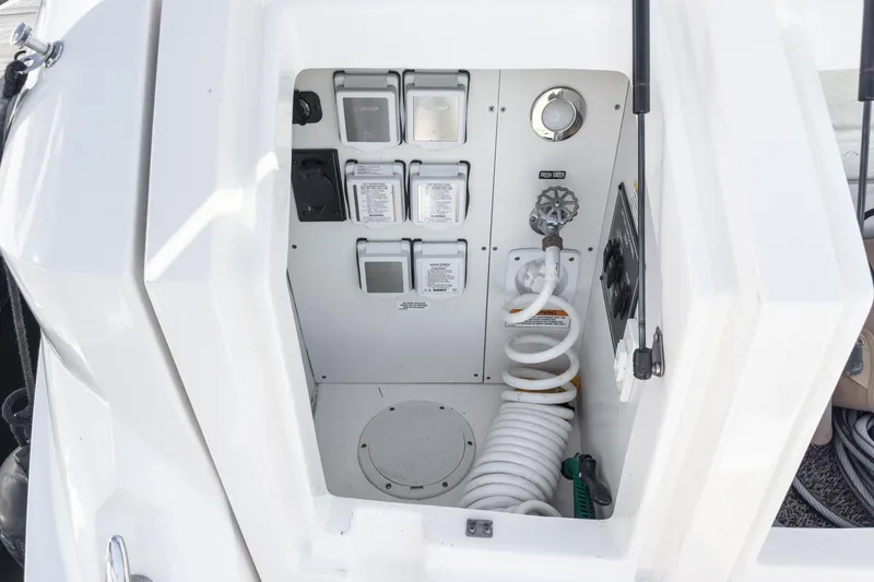 Slide: The Image of 2021 Sea Ray Sundancer 320 Outboard utility compartment with hose and controls. - 58