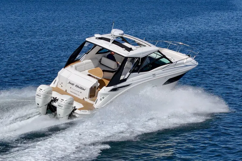 Slide: The Image of 2021 Sea Ray Sundancer 320 Outboard cruising on open water, showcasing sleek design and powerful engines. - 7