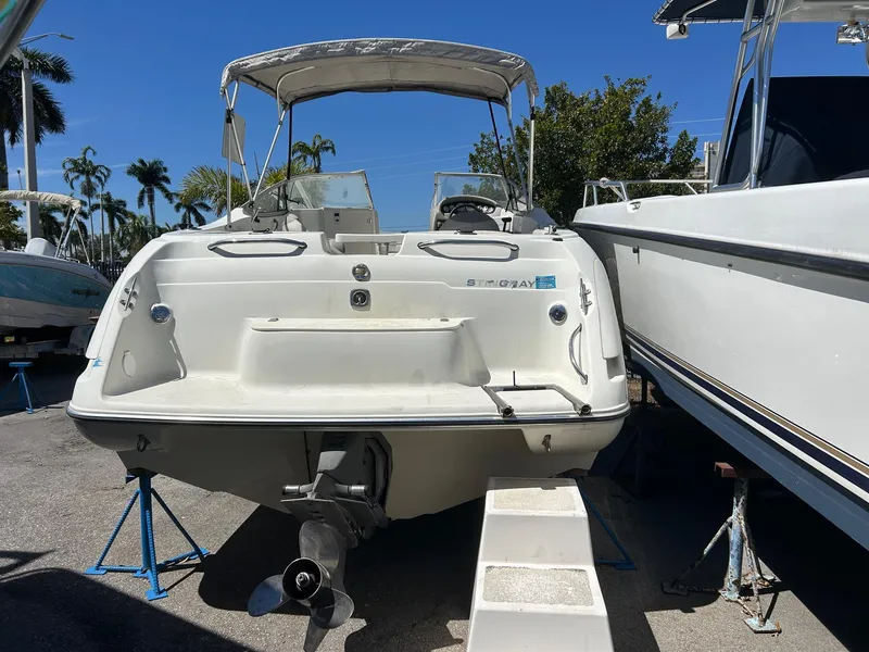 Slide: The Image of 2003 Stingray 240 LR boat on stands, rear view, sunny day, palm trees in background. - 2