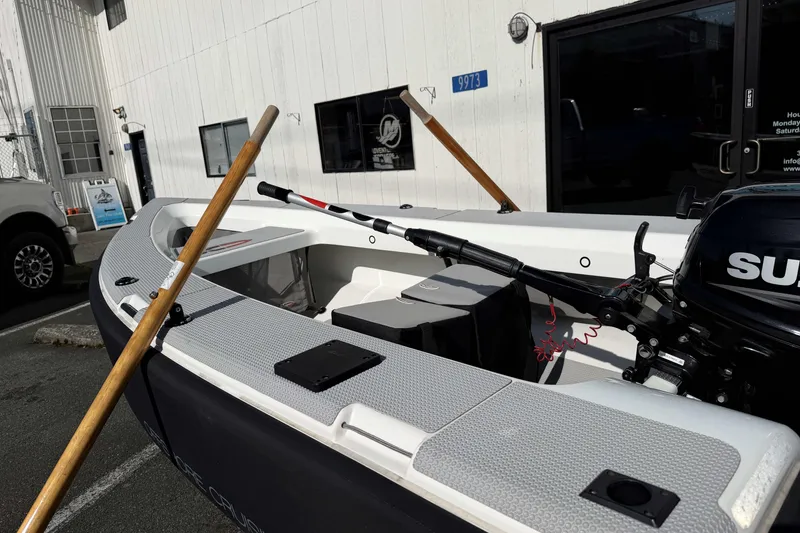 Slide: The Image of OC Tenders OC-300 boat, 2020 model, with oars and outboard motor, parked outside. - 6