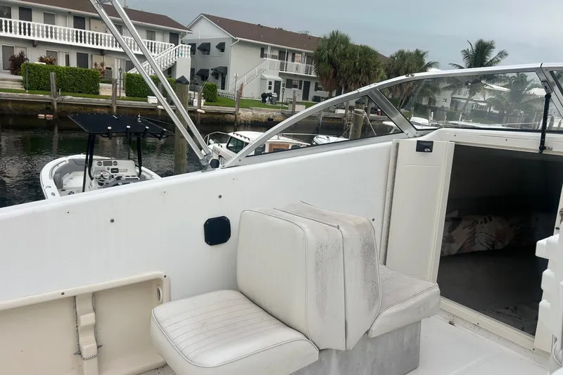 Slide: The Image of 2001 Sea Fox 204 Millenium boat interior with seating and cabin, docked near waterfront homes. - 6