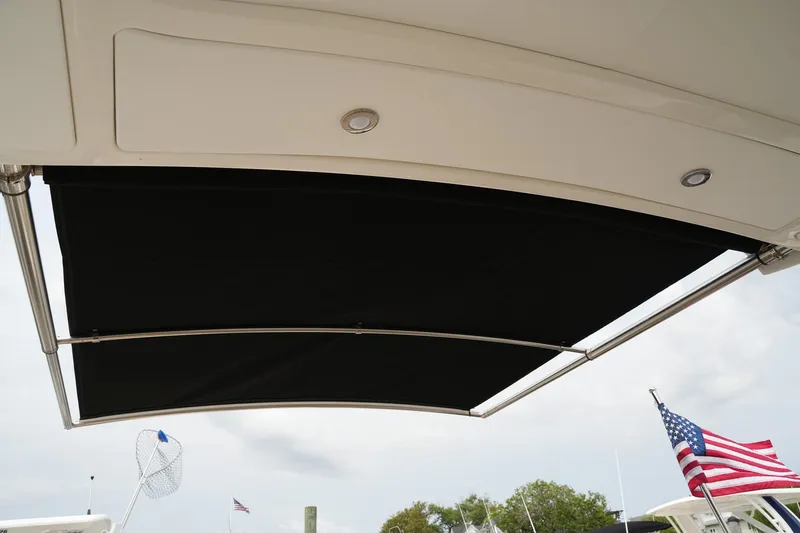 Slide: The Image of 2023 Sea Ray SLX 310 boat with extended black sunshade and American flag in background. - 18