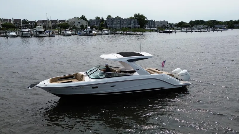 Slide: The Image of 2023 Sea Ray SLX 310 boat cruising on a calm river near a marina. - 2