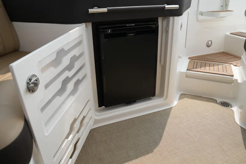 Slide: The Image of 2023 Sea Ray SLX 310 interior with mini fridge and storage compartment. - 29