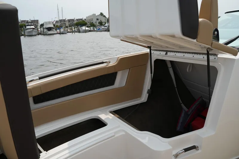 Slide: The Image of 2023 Sea Ray SLX 310 boat storage compartment open by the water. - 30