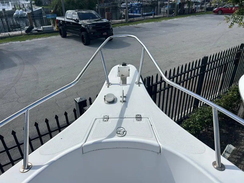 Slide: The Image of Bow view of 1998 Cobia 224 CC boat with railing, parked near a black truck. - 13