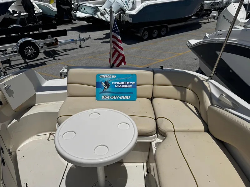 Slide: The Image of 2001 Sea Ray 240 Sundeck with beige seating and round table, displayed at a marina. - 7
