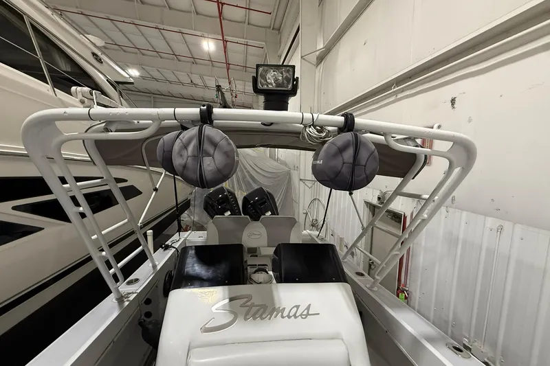 Slide: The Image of 1988 Stamas 255 Tarpon boat interior with dual engines and overhead storage in a warehouse. - 16