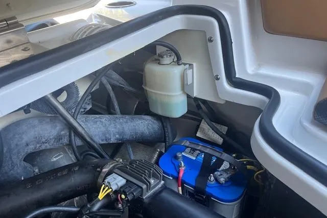 Slide: The Image of Engine compartment of a 2021 Scarab 215 ID boat, featuring battery and fluid reservoir. - 39