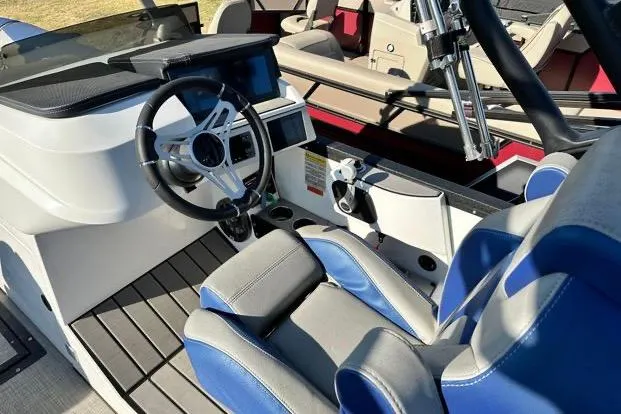 Slide: The Image of 2023 Montara 23 Surf Boss 2.0 CW boat interior with steering wheel and blue seating. - 5
