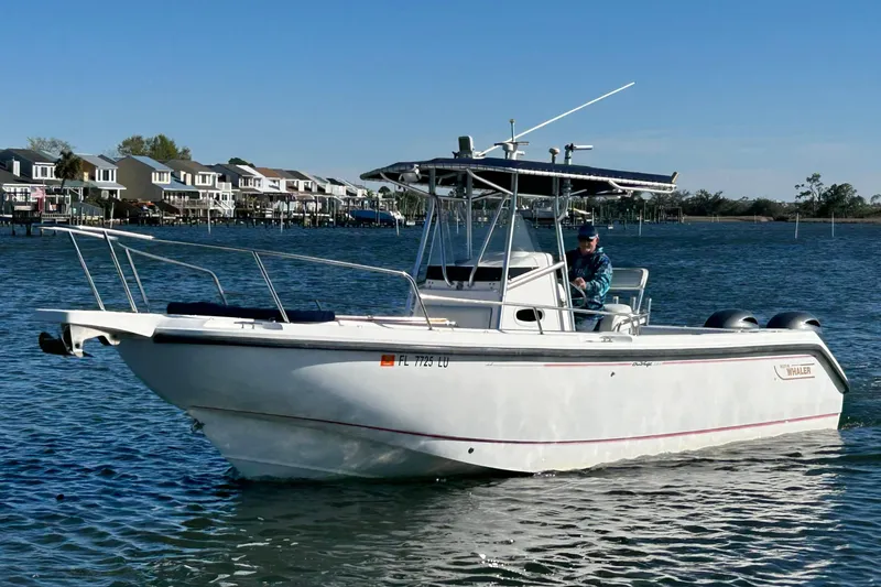 The Image of 2002 Boston Whaler 260 Outrage boat cruising on a calm waterway near residential area. - 0