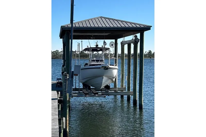 Slide: The Image of 2002 Boston Whaler 260 Outrage boat on lift under covered dock. - 3