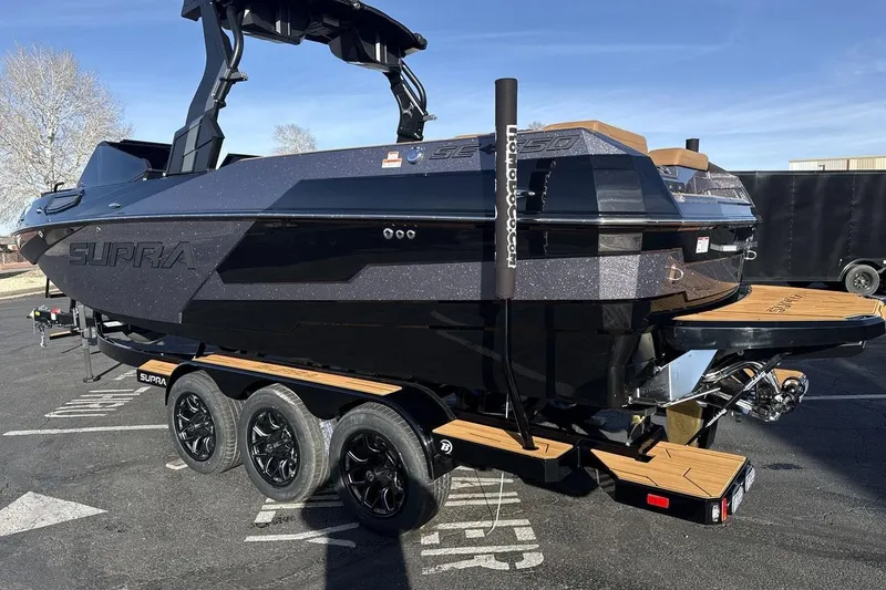 Slide: The Image of 2026 Supra SE 550 boat on trailer, sleek black design, parked outdoors. - 3