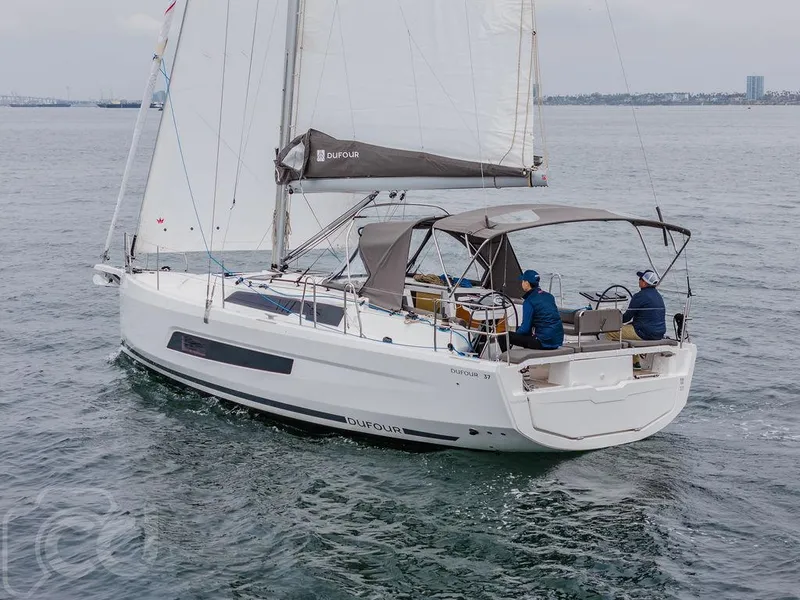 Slide: The Image of 2023 Dufour 37 sailboat docked in a marina, featuring dual steering wheels. - 11