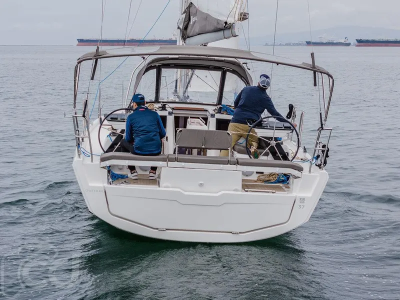 Slide: The Image of 2023 Dufour 37 sailboat on calm waters, featuring dual steering wheels and a spacious deck. - 12