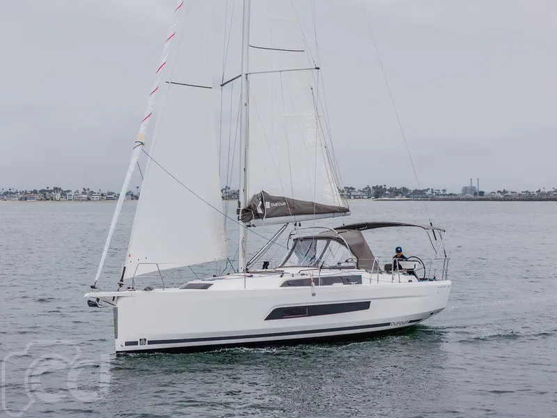 Slide: The Image of 2023 Dufour 37 sailboat docked at marina with blue sky and red umbrellas. - 2