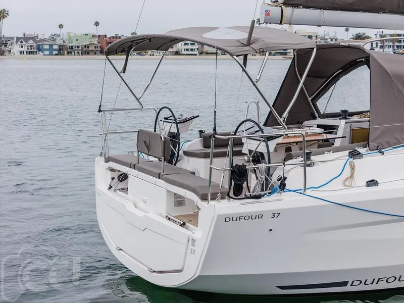 Slide: The Image of 2023 Dufour 37 sailboat on calm water, rear view showcasing deck and dual steering wheels. - 8