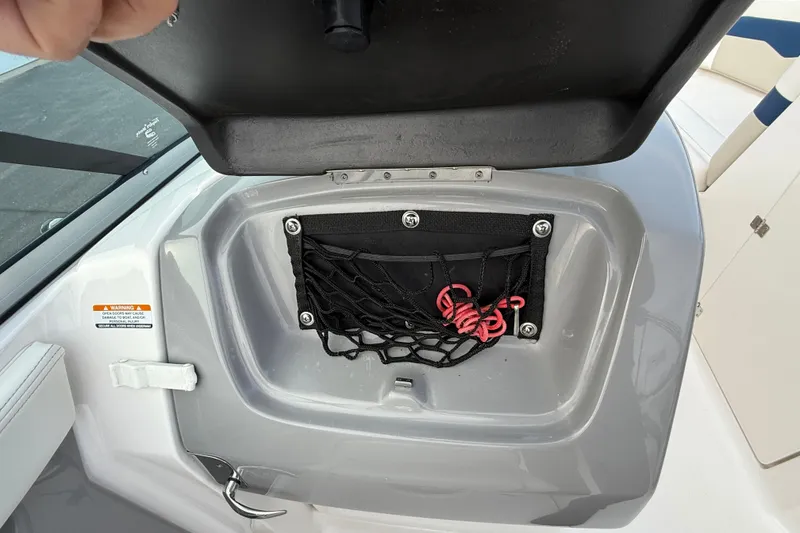 Slide: The Image of Open storage compartment on 2013 Chaparral 246 SSi boat with netting and red rope. - 12