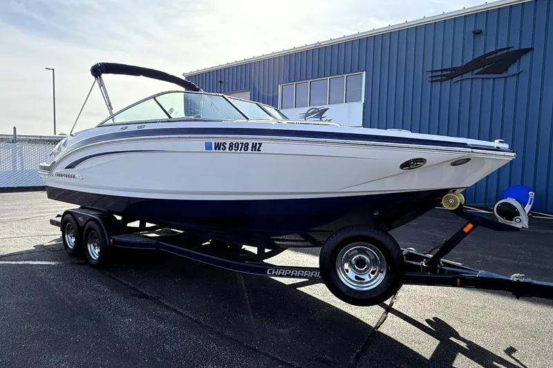 Slide: The Image of 2013 Chaparral 246 SSi boat on trailer, parked outside a blue building. - 2