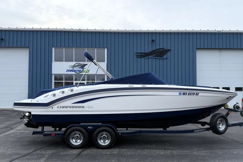 Slide: The Image of 2013 Chaparral 246 SSi boat on trailer, parked outside a blue building. - 3