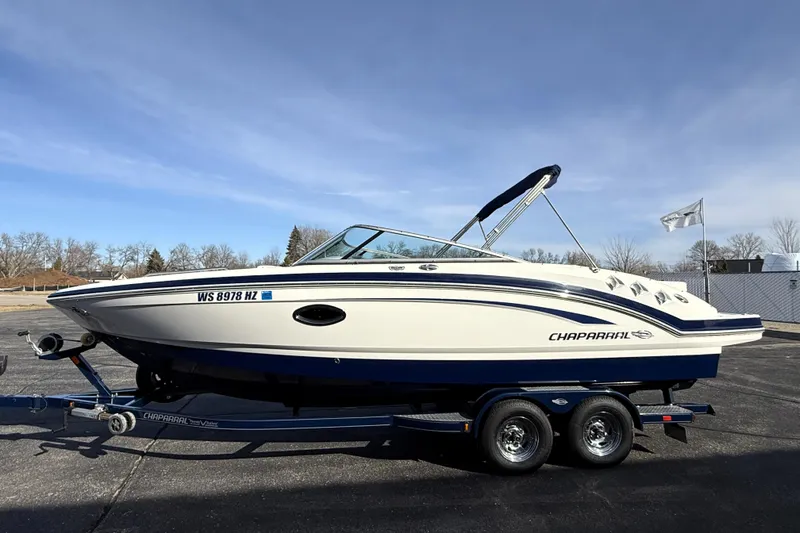 Slide: The Image of 2013 Chaparral 246 SSi boat on trailer, parked outdoors under clear sky. - 4
