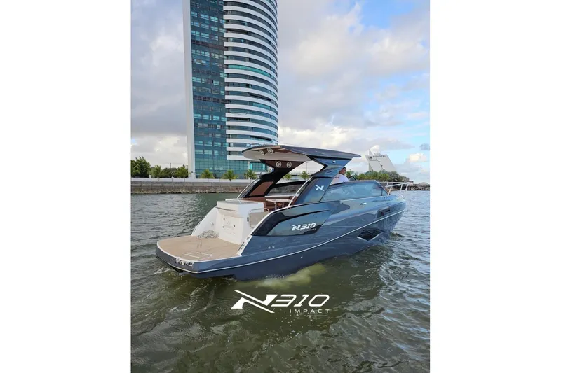 The Image of 2026 NX Boats NX310 cruising near modern waterfront building. - 1