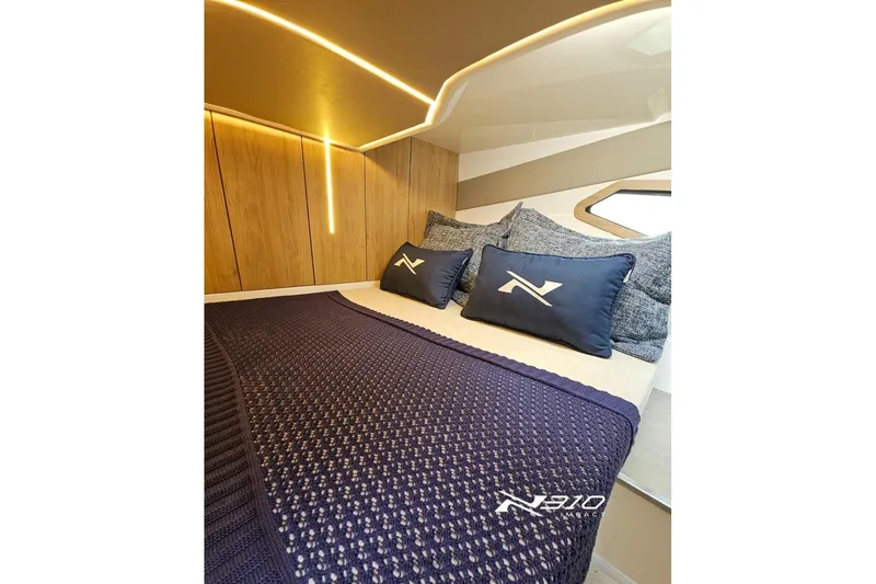 Slide: The Image of Luxurious cabin interior of 2026 NX Boats NX310 with cozy bedding and ambient lighting. - 7
