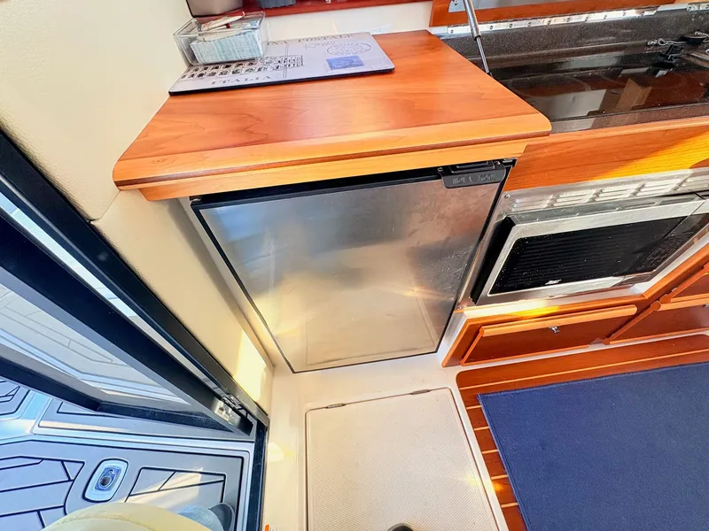Slide: The Image of Interior of 2023 Cutwater 32 Coupe with fridge and wooden countertop. - 34