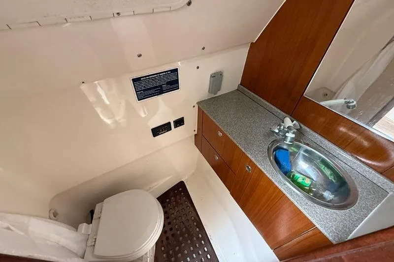Slide: The Image of 2006 Pursuit 345 Drummond Sportfish boat bathroom with sink, toilet, and wooden cabinetry. - 19