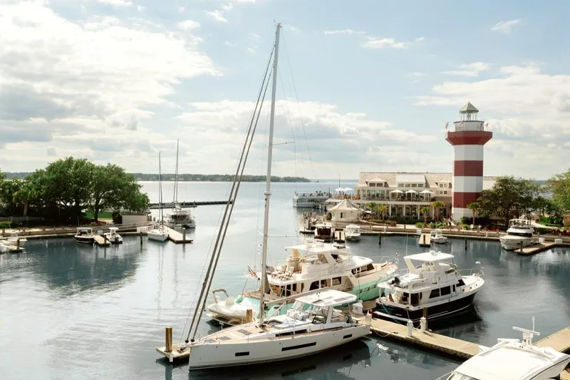 The Image of Marina with 2023 Hanse 460 sailboat, lighthouse, and boats under a cloudy sky. - 0