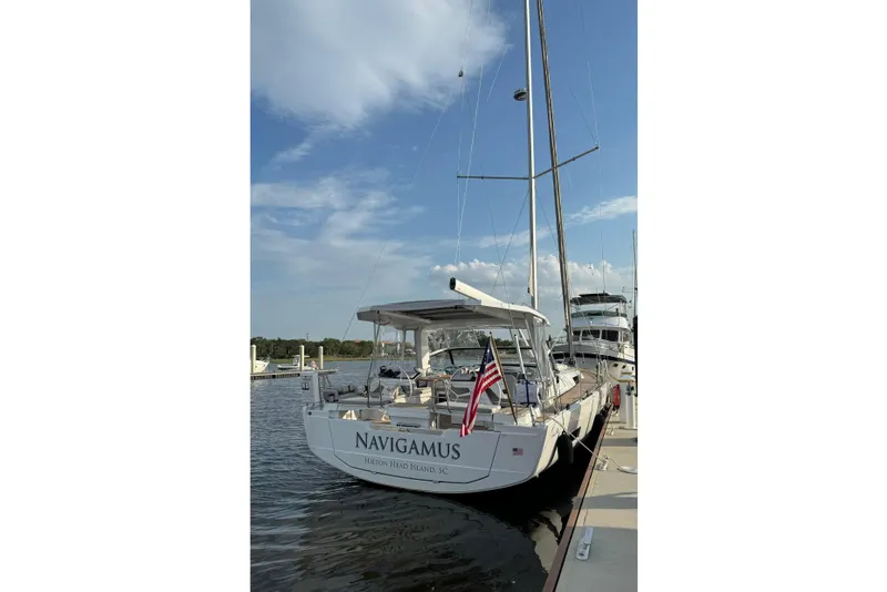 Slide: The Image of 2023 Hanse 460 sailboat docked, displaying an American flag, under a clear sky. - 2