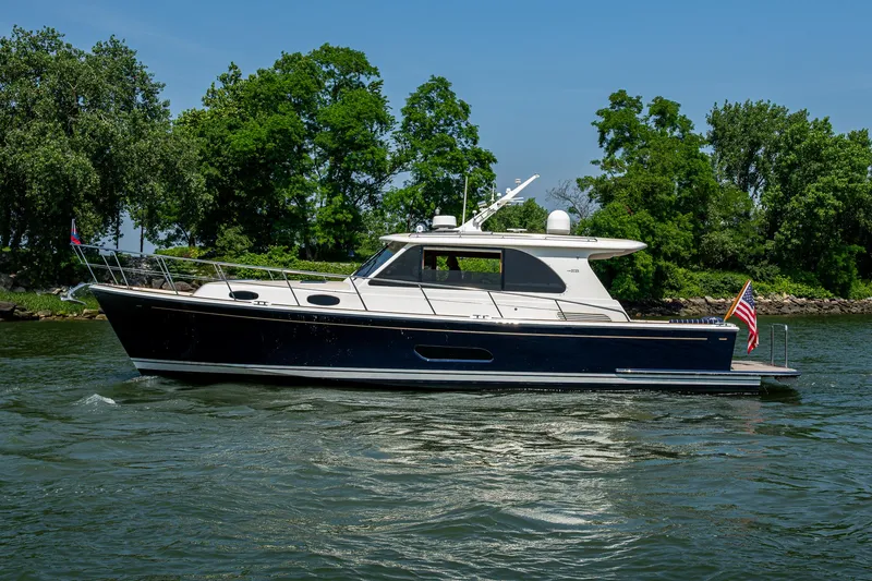 Slide: The Image of 2017 Grand Banks 44 Eastbay SX yacht cruising on a scenic waterway with lush greenery. - 6