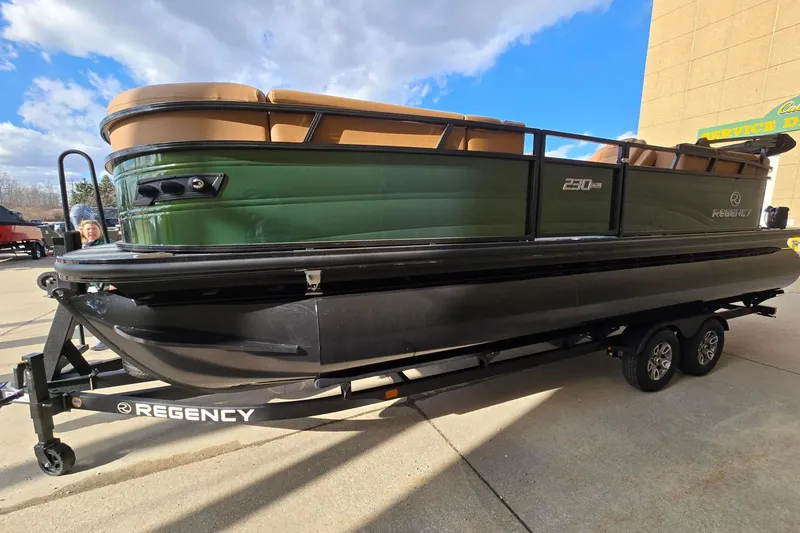 Slide: The Image of 2026 Regency 230 DL boat on trailer, parked on a sunny day. - 2